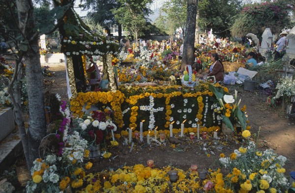 MEXICO, Michoacan State, Patzcuaro, Tomb in Tzurumutaro Cemetary decorated with flowers fruit and candles for Day of the Dead celebrations.