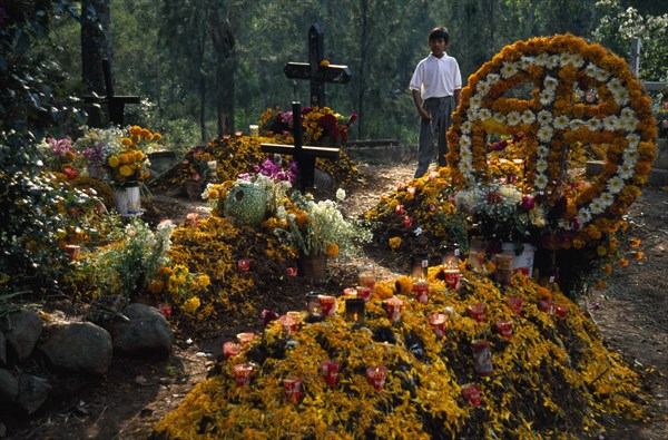 MEXICO, Michoacan State, Patzcuaro, Graves in Tzurumutaro Cemetary decorated with flowers fruit and candles for Day of the Dead celebrations.