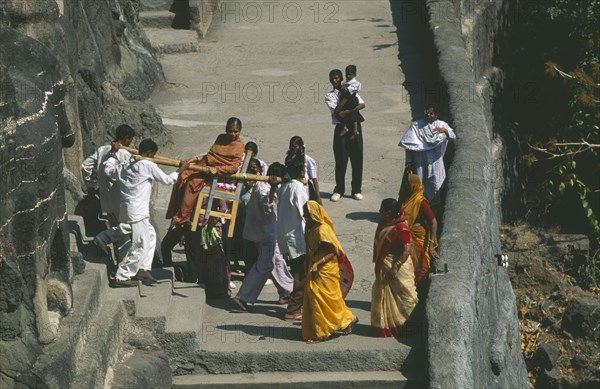 INDIA, Maharashtra, Ajanta, Woman being carried around the Ajanta Buddhist caves on a wooden chair