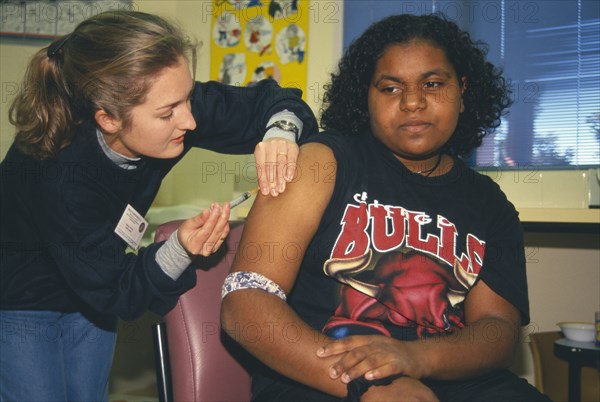 AUSTRALIA, Western Australia, Kalgoorlie, Aboriginal girl receiving Rubella vaccination from female nurse.