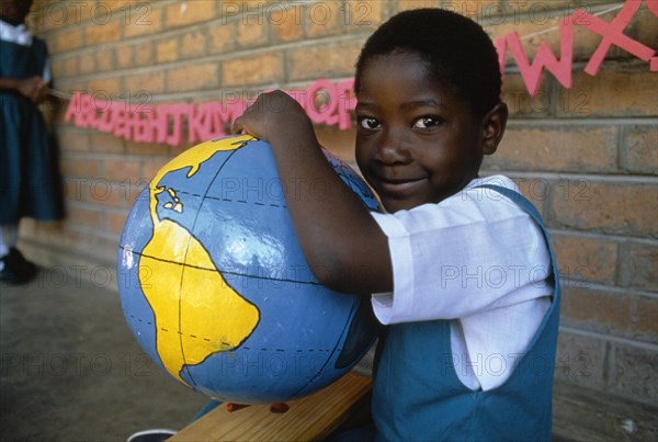 MALAWI, Blantyre, Schoolgirl with papier mache globe teaching aid made by PAMET who recycle everything from newspapers to elephant dung