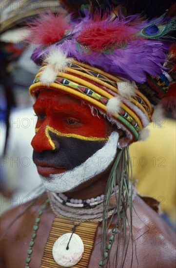 PAPUA NEW GUINEA, Tribal People, Eastern Highlander with head dress made of dyed chicken feathers and heavily painted face at Goroka Show.