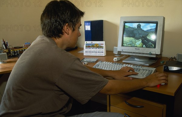 SPAIN, Madrid, Teenage boy using computer to play game.