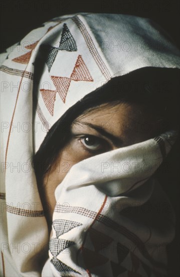 TUNISIA, People, Women, Young woman with face half hidden by head dress.