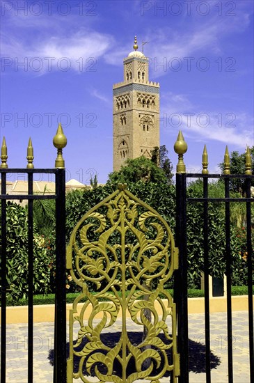 MOROCCO, Marrakech, View through black and gold wrought iron gate towards the minaret of Koutoubia Mosque