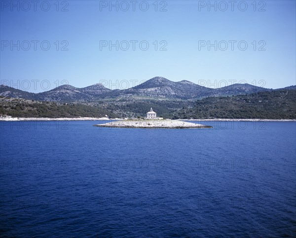 CROATIA, Dalmatia, View over water toward small islet between Sibenik and Trogir with lighthouse in the centre