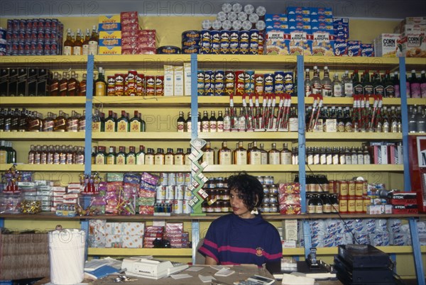 DOMINICAN REPUBLIC, Shop, Woman behind counter in general store in front of goods on shelves behind her