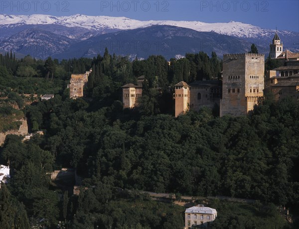SPAIN, Andalucia, Granada, Alhambra Palace walls and towers seen from Mirador San Nicolas with the snow covered Sierra Nevada beyond