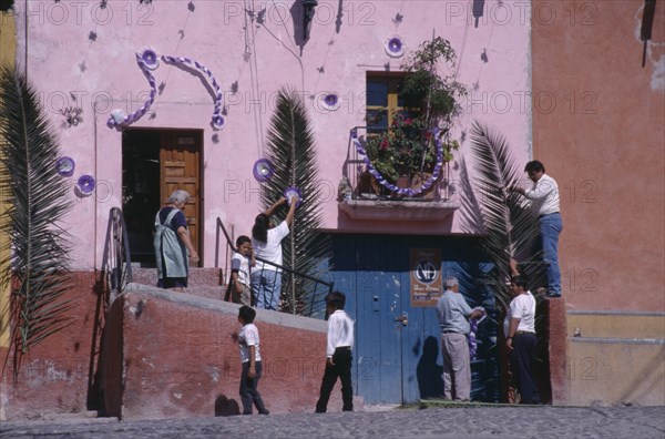 MEXICO, Guanajuato, San Miguel de Allende, People decorating exterior of house with palm fronds and streamers for Palm Sunday celebrations.