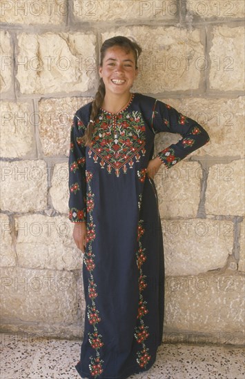 WEST BANK, People, Young woman in traditional Palestinian embroidered dress in National colours