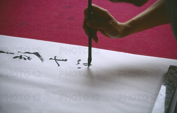 CHINA, Sichuan, Leshan, Cropped view of person writing traditional Chinese caligraphy.