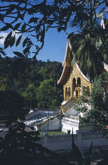 LAOS, Luang Prabang, Royal Palace.  Exterior of temple part framed by tree branches.