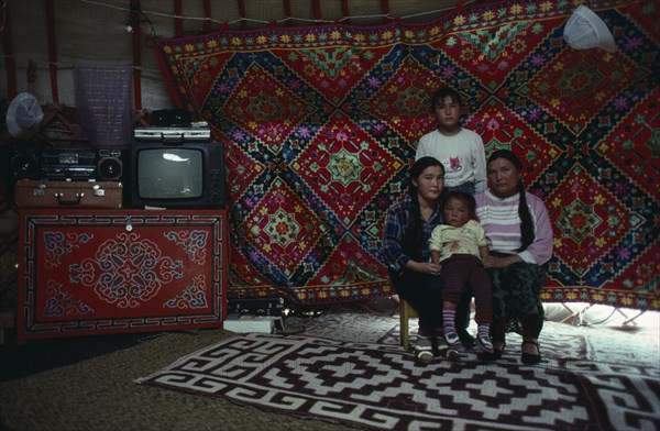 MONGOLIA, People, Mongolian mother and children inside a yurt sitting beside stereo and television