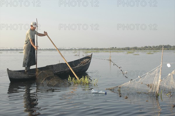 ROMANIA, Tulcea, Danube Delta Biosphere Reserve, Professional fisherman in canoe on Lake Isac checking his nets