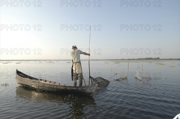 ROMANIA, Tulcea, Danube Delta Biosphere Reserve, Professional fisherman in canoe on Lake Isac checking his nets