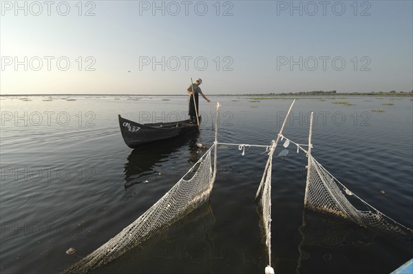 ROMANIA, Tulcea, Danube Delta Biosphere Reserve, Professional fisherman in canoe on Lake Isac checking his nets