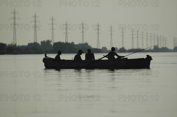 ROMANIA, Tulcea, Danube Delta Biosphere Reserve, Silhouette of a two canoes with sports fishers on the Sulina arm of the Danube river