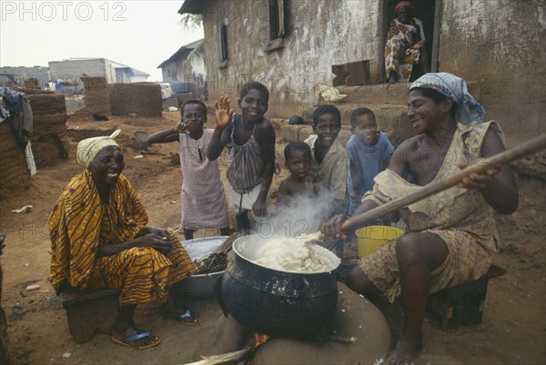 GHANA, Near Accra, Women and children cooking Fufu the national delicacy of pounded yams in a small village near the capital city
