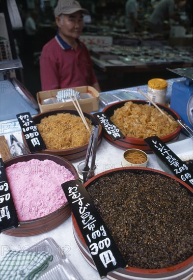 JAPAN, Honshu, Tokyo, Tsukiji Fish Market stall with variety of seafood items on dispay and vendor in the background