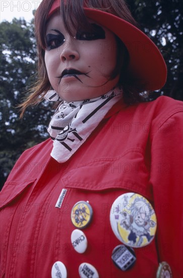 JAPAN, Honshu, Tokyo, Harajuku District. Portrait of young teenage girl wearing a red jacket and elaborate punk style makeup and piercing