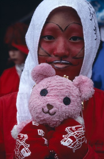 JAPAN, Honshu, Tokyo, Harajuku District. Portrait of young teenage girl wearing red face paint and holding a pink teddy bear