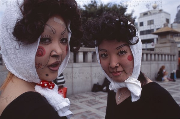 JAPAN, Honshu, Tokyo, Harajuku District. Portrait of two young teenage girls wearing theatrical face makeup and white headscarfs