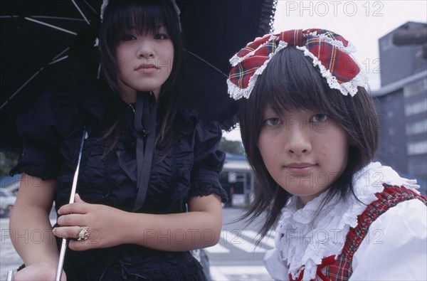 JAPAN, Honshu, Tokyo, Harajuku District. Portrait of two young teenage girls with one wearing black and the other wearing tartan