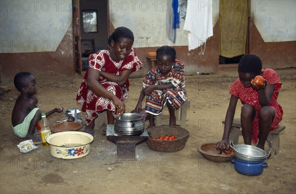 GHANA, Cooking, Woman with children cooking Abenkwan or palm nut soup a thick broth made from the pulp of boiled palm fruit with added fish or meat and spices.