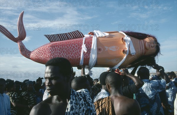 GHANA, Teshie, Coffin made and painted to resemble a mermaid for Ga tribal priestess of sea god carried by funeral guests.