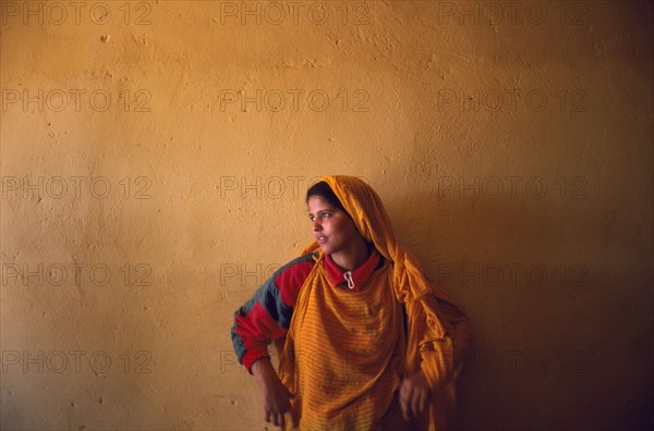 WESTERN SAHARA, Polisario Front, Saharawi girl standing in front of wall painted deep ochre colour.