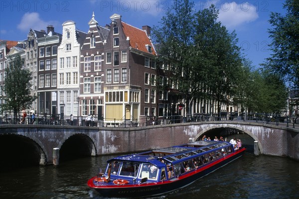 HOLLAND, Noord, Amsterdam, Tourist boat passing under a bridge on the Keizersgracht canal