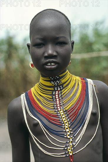 SUDAN, Body Decoration, "Young Dinka girl wearing multi stranded necklace made from tiny yellow, red, blue and white coloured beads"