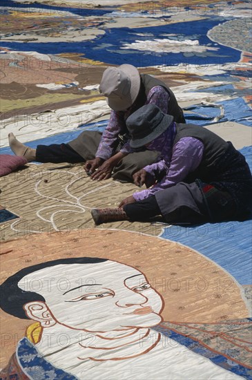 CHINA, Tibet, Lhasa, Potola Palace.  Workers sewing huge Buddha Tankha spread out on floor.