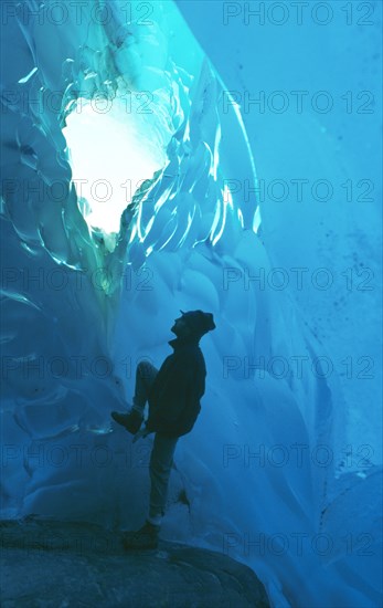 ARGENTINA, Patagonia, Santa Cruz, "Parque Nacional Los Glaciares, Glaciar Viedma.  Interior with climber looking up through hole in ice roof. "