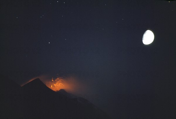 ITALY, Aeolian Islands, Stromboli, Night view of the active volcano hourly eruption with moon behind