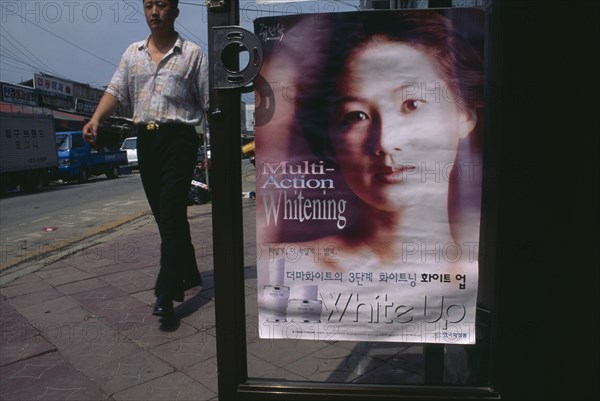 SOUTH KOREA, Sokcho, Man walking past advertisment for skin whitening cream