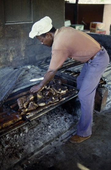 WEST INDIES, Jamaica, "Food ", Man cooking jerk pork over an open fire
