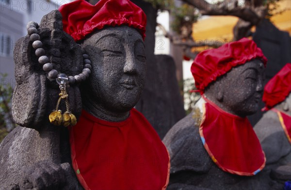 JAPAN, Honshu, Kamakura, Row of Jizo statues dressed in red bibs by bereaved mothers and other sufferers