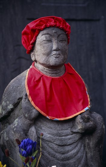 JAPAN, Honshu, Kamakura, Jizo statue traditionally dressed in red bibs by bereaved mothers and other sufferers