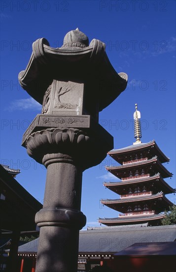 JAPAN, Honshu, Tokyo, Asakusa. Senso Ji Temple. Angled view of the Five Storey Pagoda with ornamental stone column in the foreground