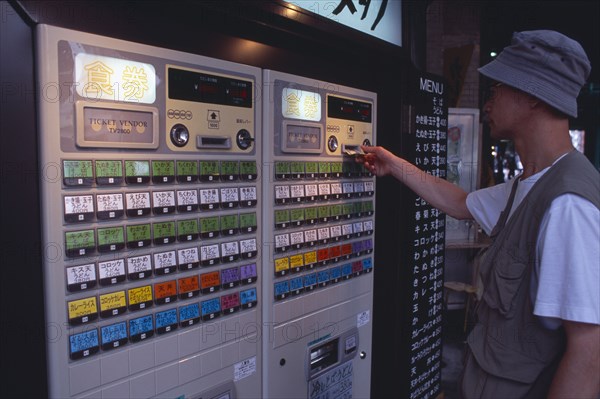 JAPAN, Honshu, Tokyo, Shimbashi. Man using Restaurant Ticket vending machine