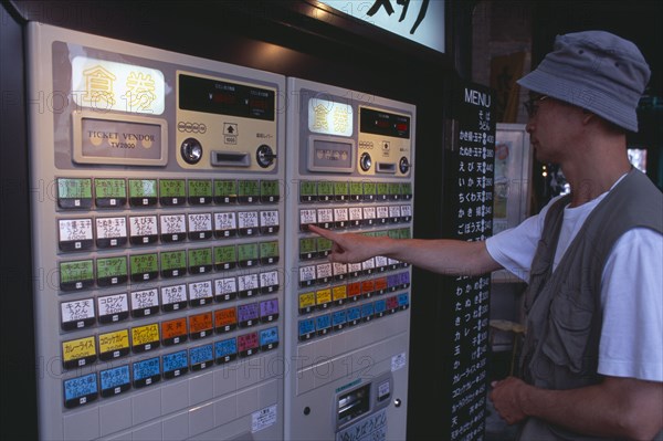 JAPAN, Honshu, Tokyo, Shimbashi. Man using Restaurant Ticket vending machine