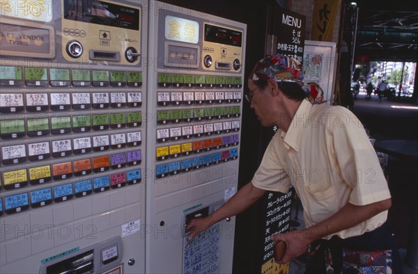 JAPAN, Honshu, Tokyo, Shimbashi. Man using Restaurant Ticket vending machine