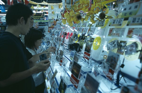 JAPAN, Honshu, Tokyo, Shinjuku. Customers browsing in Camera shop interior with illuminated displays