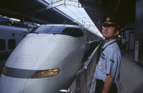 JAPAN, Honshu, Kyoto, Bullet train aka Shinkansen pulling into the station platform with train guard standing in the foreground