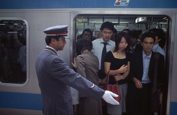 JAPAN, Honshu, Tokyo, Passengers on crowded train at Ueno Station with train guard standing on the platform