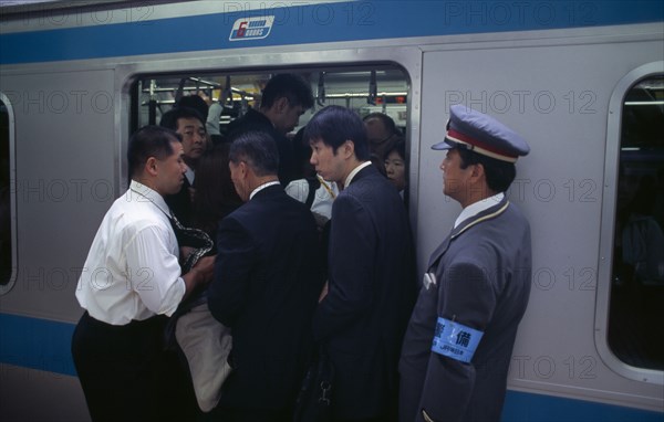 JAPAN, Honshu, Tokyo, Passengers crowding on to a train at Ueno Station with train guard standing on the platform