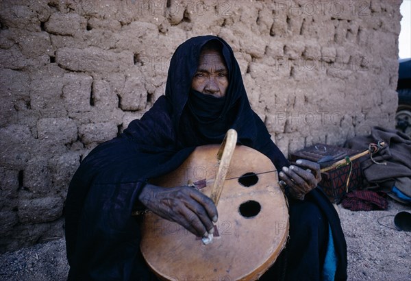 NIGER, General, Tuareg woman playing an Imzad.  A traditional instrument consisting of a goatskin covered gourd or wooden resonator played with a curved bow and horsehair string.