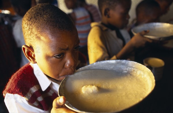 TANZANIA, Singida, Boy drinking from bowl of breakfast at the Kititimo Centre School for street children.