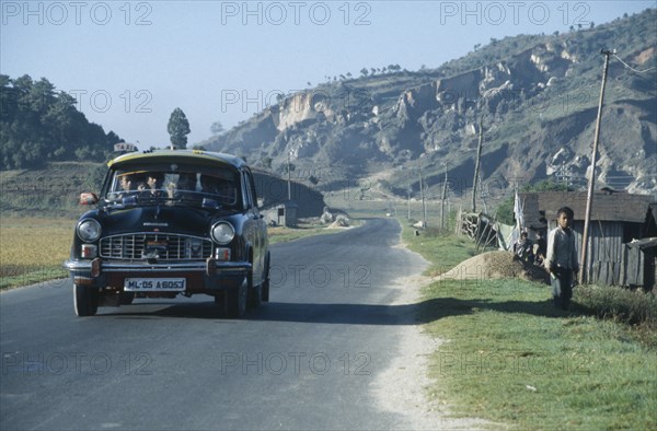 INDIA, Meghalaya, Packed ambassador taxi on road through rural area in north east India.